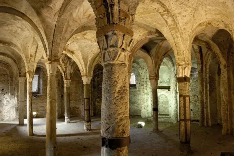 Interno della Cripta di Sant'Eusebio a Pavia con i caratteristici capitelli alveolati longobardi e volte a crociera medievali illuminate.