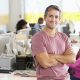Portrait Of Man Standing In Busy Creative Office Portrait Of Man Standing In Busy Creative Office