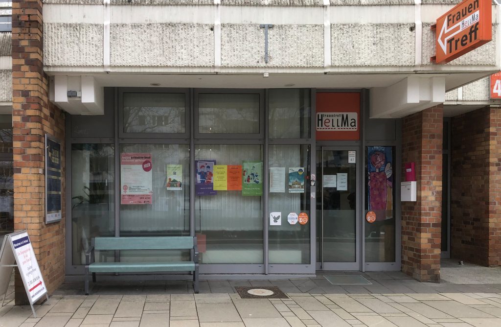 Außenansicht des Frauentreffs HellMa in einem Laden in der Marzahner Promenade , an den Schaufenstern hängen Plakate für verschiedene Veranstaltungen für Frauen.