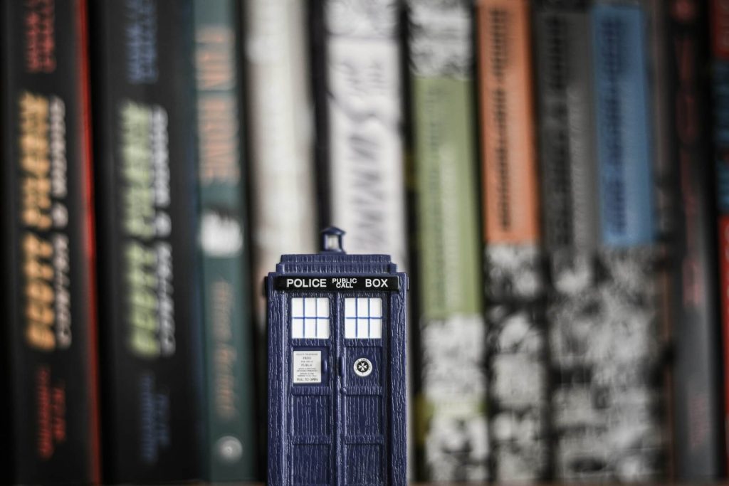 Una TARDIS, la cabina de Doctor Who, delante de un estante de libros