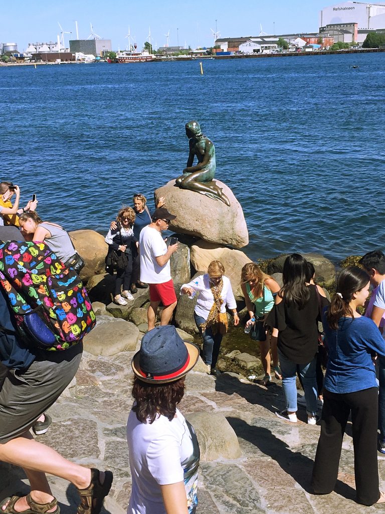 Tourists waiting in line to take pictures with the little mermaid sculpture