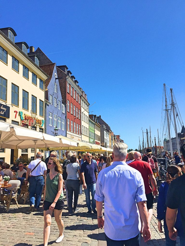 A picture of tourists walking in an area called Nyhavn