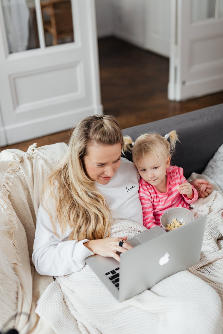 blonde girl sitting beside the woman with a laptop