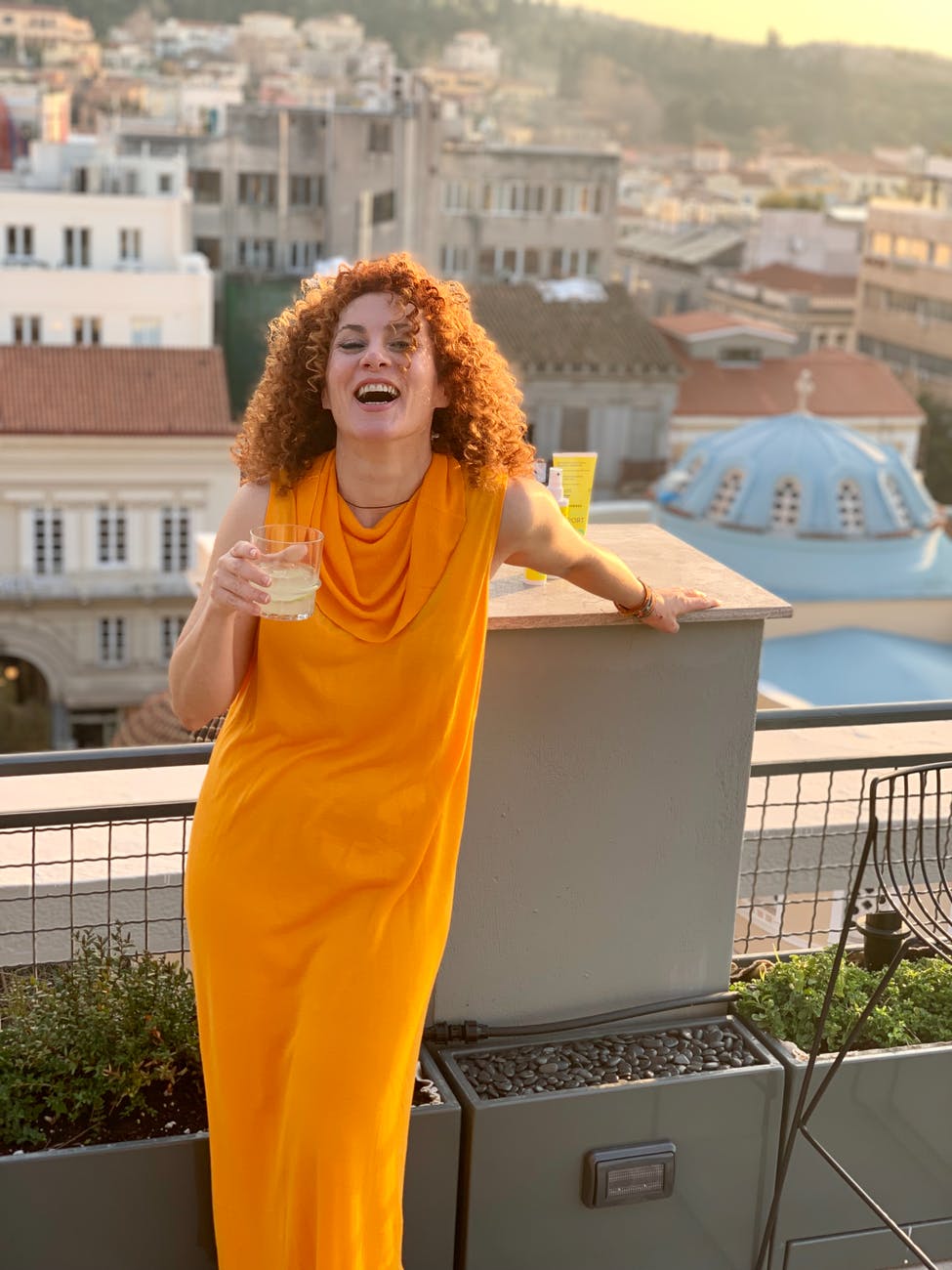 woman in an orange dress poses in the balcony