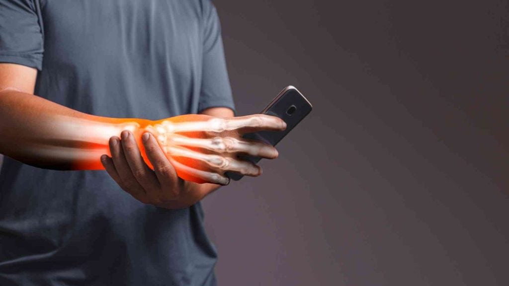 Mensch hält sein schmerzendes Handgelenk, während eine digitale Durchleuchtung die Knochenstruktur und eine Entzündungsstelle hervorhebt.