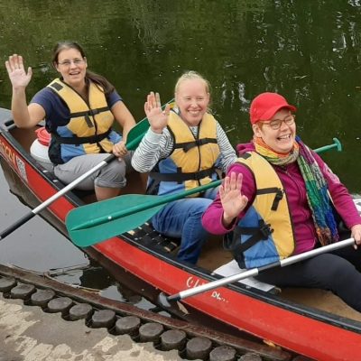 Drei Frauen paddeln fröhlich in einem Kanu bei einer Aktivreise mit den Reisegefährtinnen, dem Reiseunternehmen für Frauenreisen.