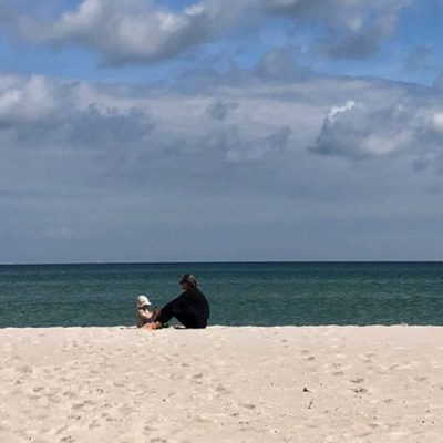 Eine Frau spielt mit einem Kind am Strand auf einer unserer Reisen für Frauen mi Kindern