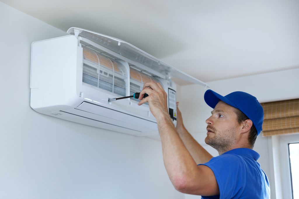 hvac services - technician installing air conditioner on the wall at home