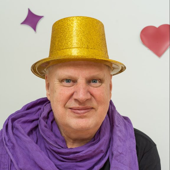 Person med guldfärgad hatt och lila scarf.