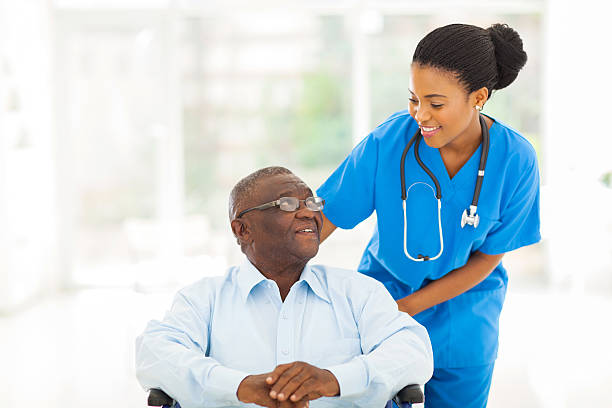 beautiful african nurse taking care of senior patient in wheelchair