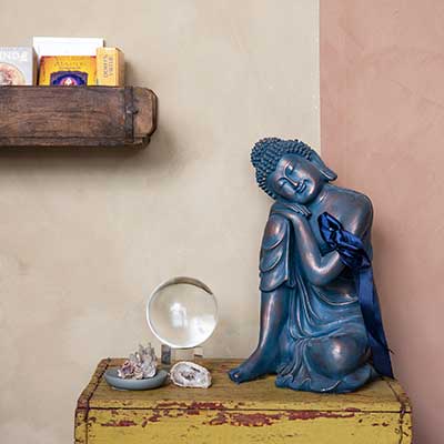 Buddha figur og krystalkugle og sten på et lille bord