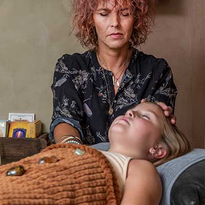 Renée Jagd sidder og laver healing på et barn der ligger ned