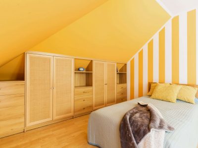 Attic bedroom with intense yellow walls and fitted wardrobe