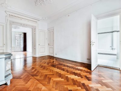 Classic home interior design of spacious hallway with white walls and decorative stucco elements and with parquet floor furnished with fireplace