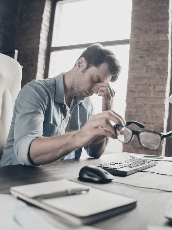 Überlasteter Unternehmer sitzt verzweifelt und depressiv am Schreibtisch vor seinem Computer