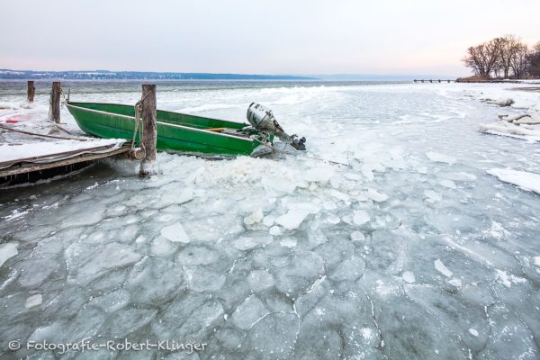Ein Motorboot im Eis des Ammersees an einem eiskaltem Wintermorgen