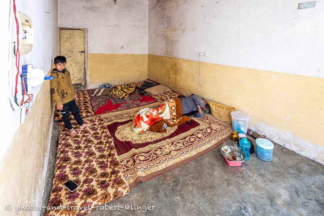 Ein Junge und sein schlafender Vater in ihrem Wohnzimmer in Kurdistan im Irak