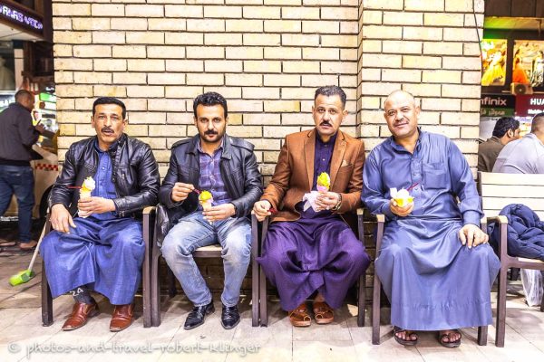 Vier kurdische Männer sitzen im Bazar von Erbil im Irak und essen Eis