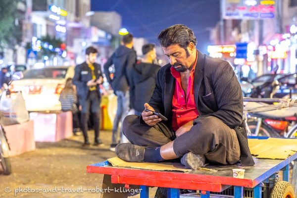Ein kurdischer Mann sitzt in Erbil im Irak auf einem Wagen und bedient sein Smartphone