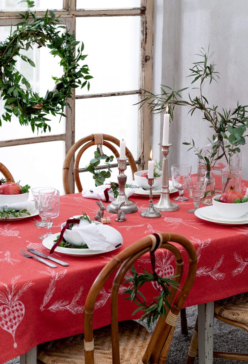 Christmas table by a window, candelabra, plates, glasses och flowers.