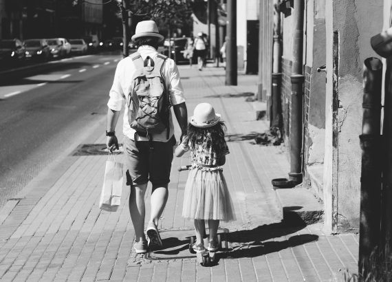 man holding girl while walking on street