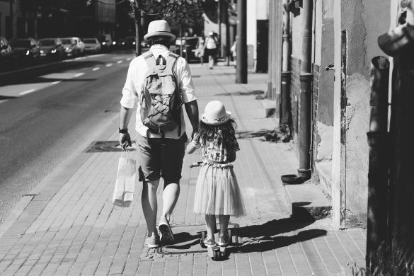 man holding girl while walking on street