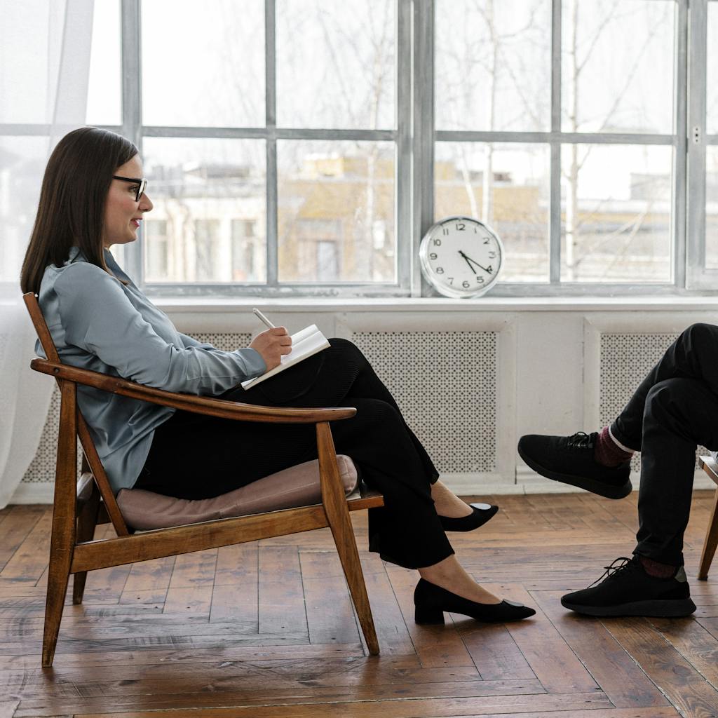 A therapist engaging in a counseling session with a male patient to support mental health.
