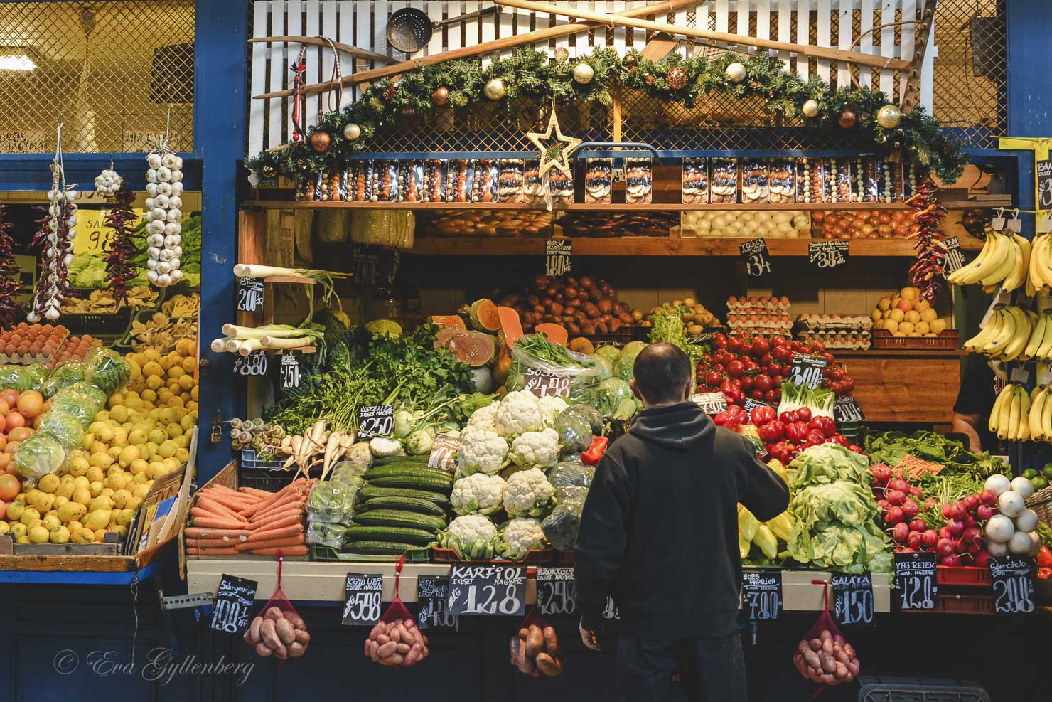 People buy vegetables in the large market hall in Budapest.