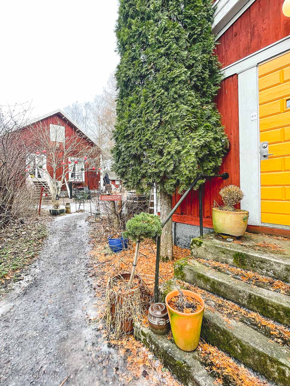 Two red wooden houses with a yellow door and a staircase