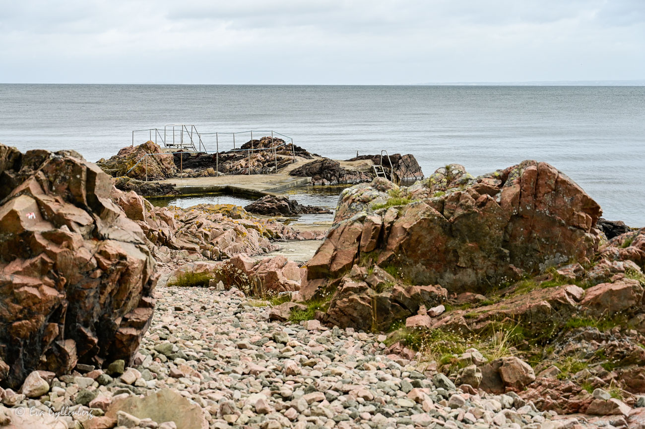 Swimming area by red cliffs and calm sea