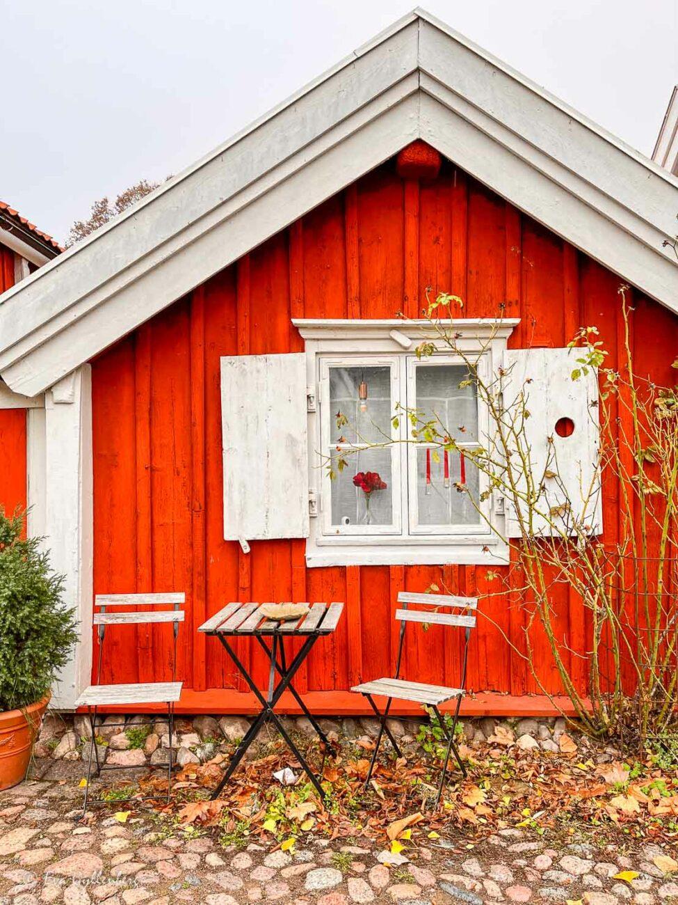 Ett litet rött hus med bord och stolar utanför i gamla stan i Kalmar