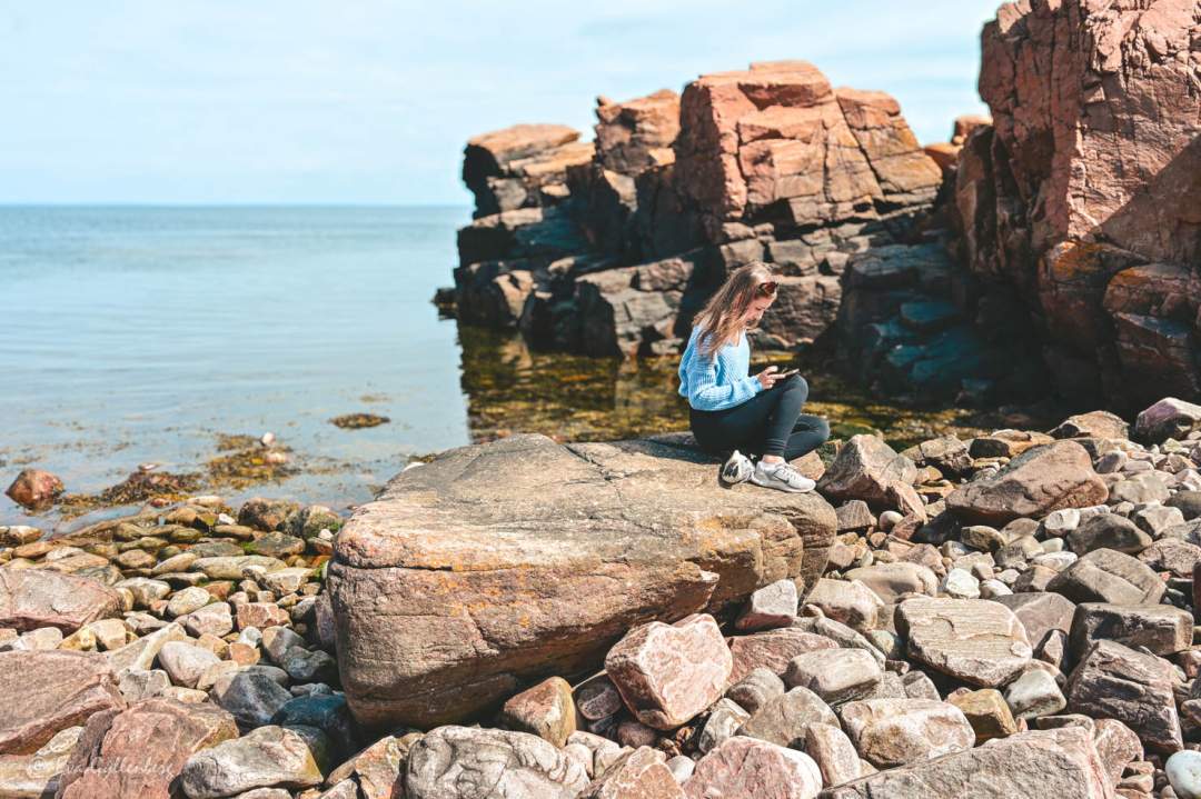 Tjej sitter på en klippa vid havet i Hovs hallar