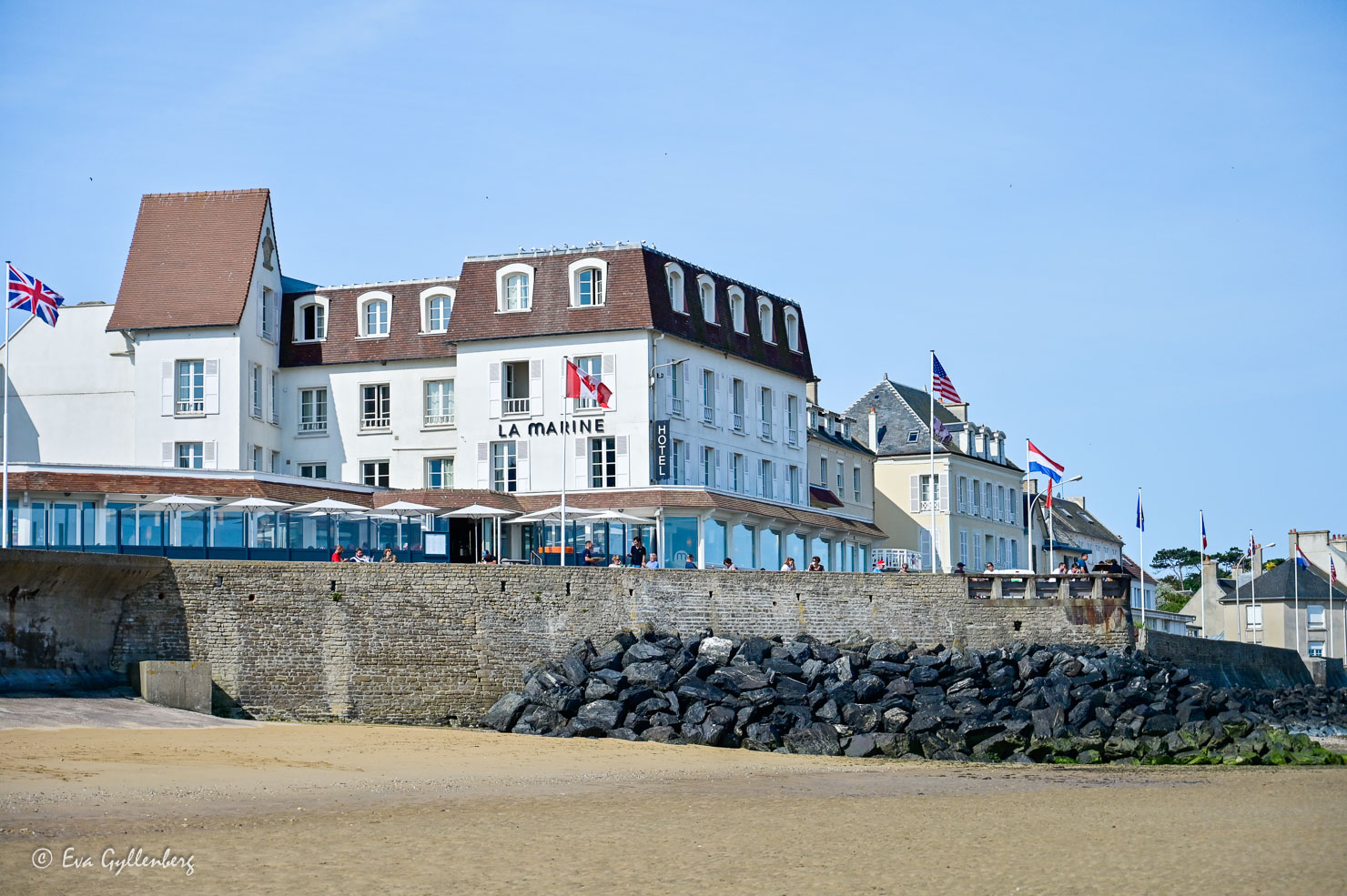 White house with restaurant and flags by a beach