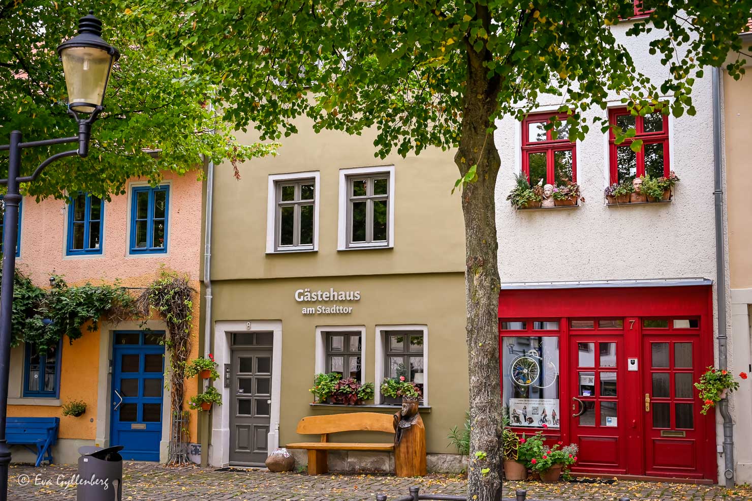 Tre hus på rad i aprikos, grönt och vitt med vackra bänkar