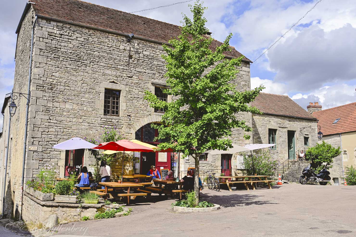 Benches with people outside a stone house in Burgundy