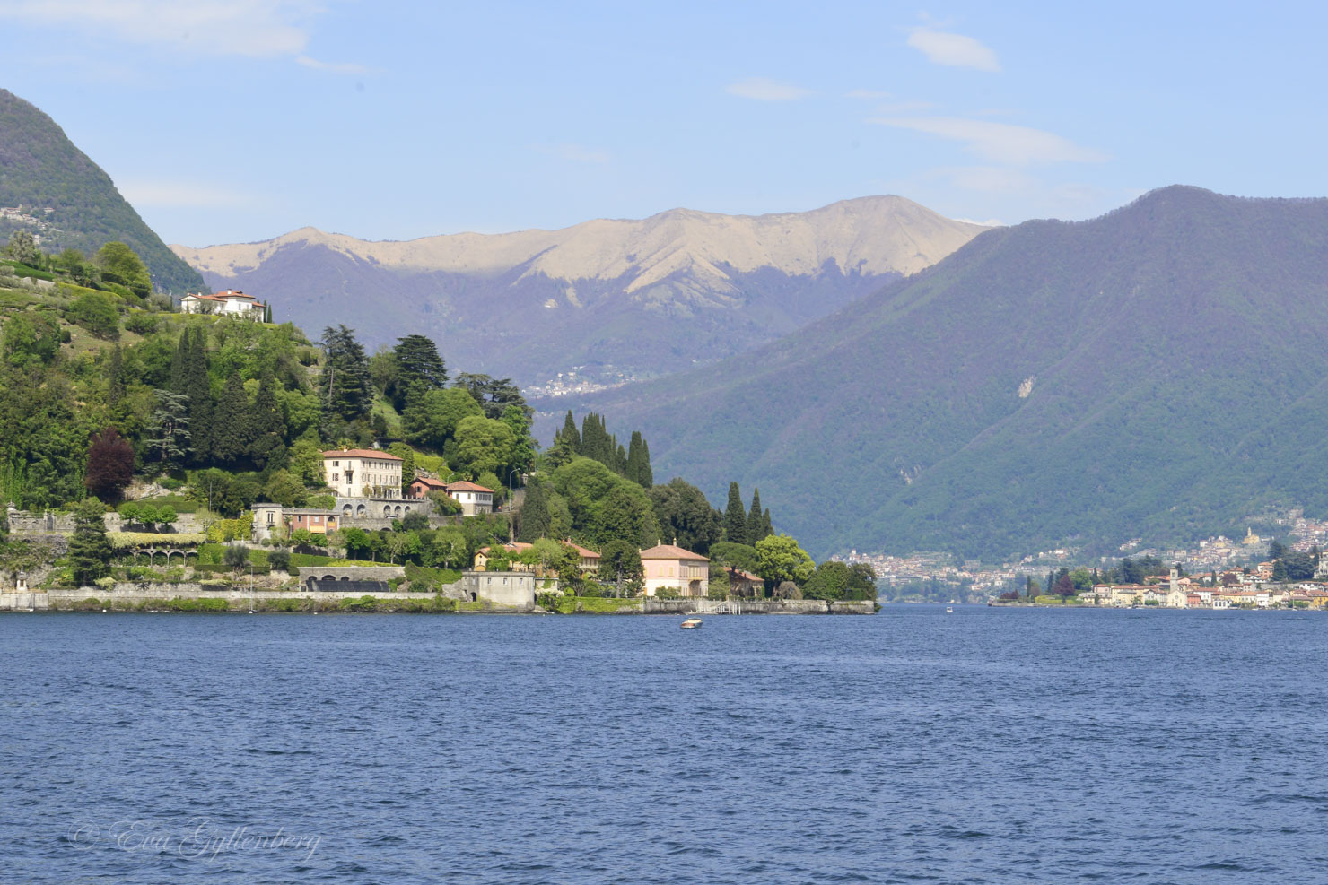 Lake Como in sunshine with houses and mountains in the background