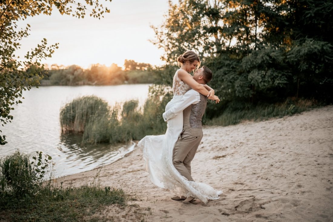 Hochzeitsfotografie: Brautpaar posiert am See während des Sonnenuntergangs im Seehaus Forst