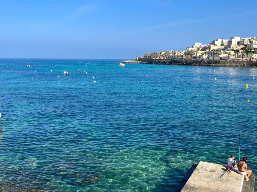Blick aufs klare Meer und Angler im Hafen von Marsaskala, Malta