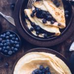 Pannekaker på brune tallerkner med blåbær og kremost