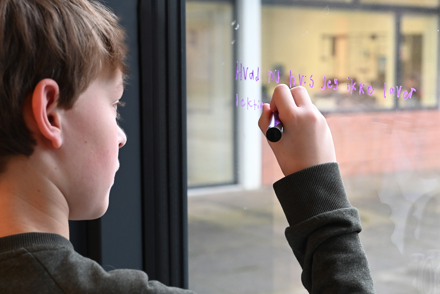 Person skriver på en vinduesrude med lilla tusch
