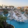 A wide photograph showing the beautiful pool area, earthy architecture and palm trees at Stella Blue.