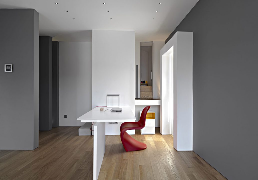 interiors shots of a modern working area in the foreground the contemporary writing desk with a red chair the floor is made of wood