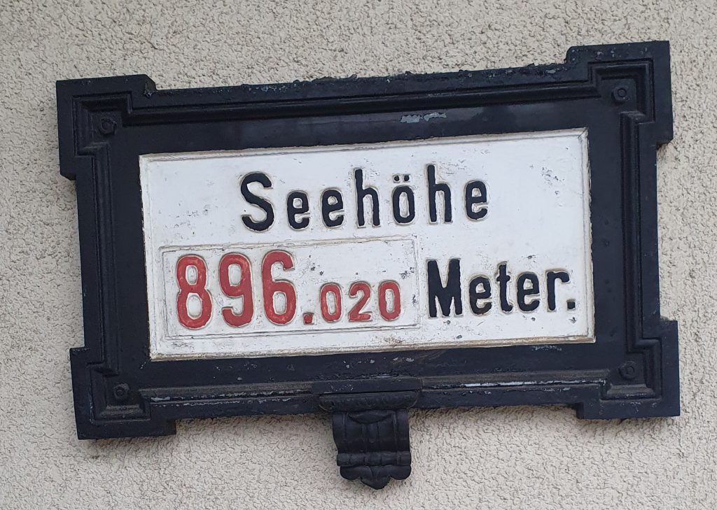 Seehöhe 896,020 Meter auf einem Schild mit Metallrahmen