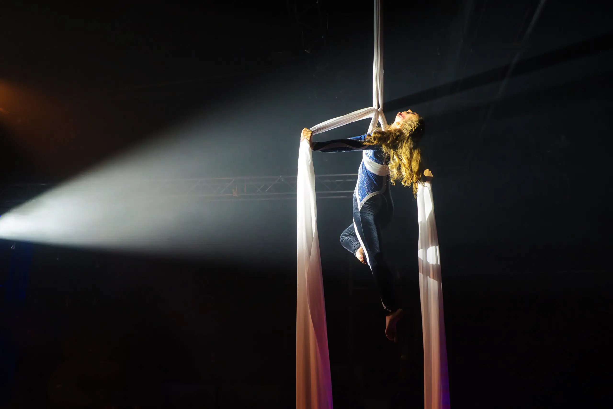 Artistik-Performance, professionell eingefangen vom Event Fotograf. Frau mit Tüchern seilt sich von der Decke ab.