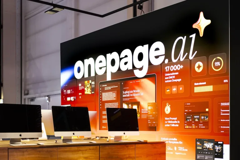 Messe Fotografie auf der Messe Düsseldorf – Onepage.ai Markenwand mit iMac-Präsentation am Messestand