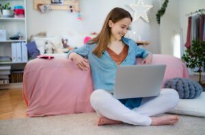 Beautiful happy young girl with laptop sitting and smiling, online dating concept