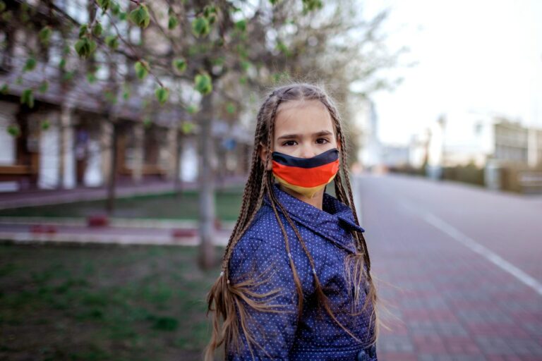 Girl wearing off the respirator medical mask in national German colors because of the end of