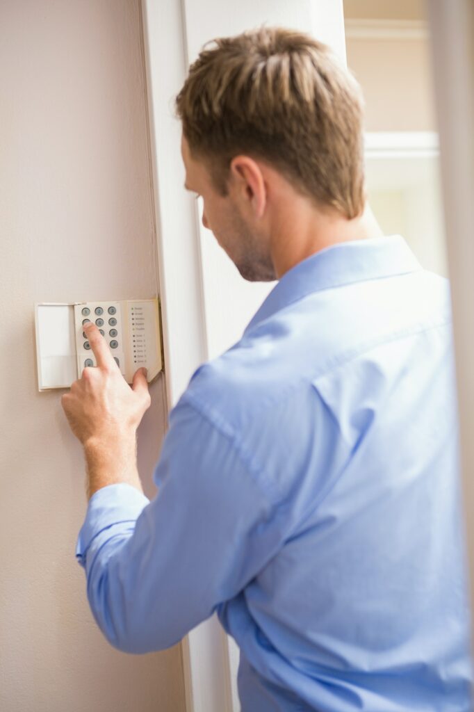 Man arming a home alarm on the wall