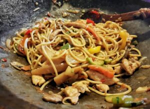 Asian food in a wok. Noodles with chicken and vegetables.