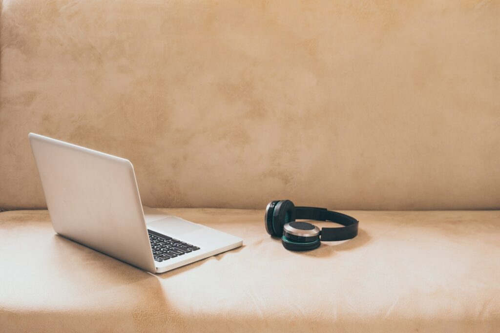 Laptop and headphones on sofa at home.